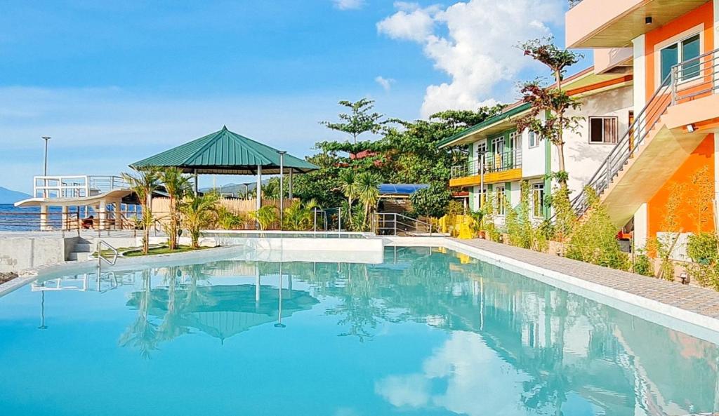 a swimming pool in front of a building at RedDoorz Plus @ Galucksea Beach Resort in Caore