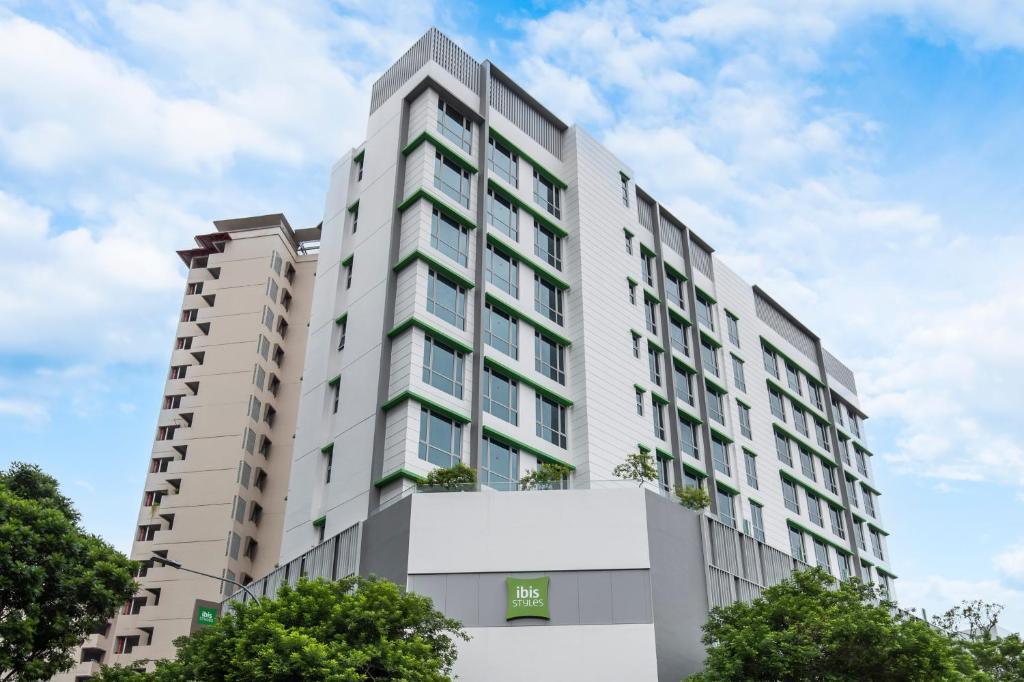 ein hohes weißes Gebäude mit Bäumen davor in der Unterkunft ibis Styles Singapore Albert in Singapur