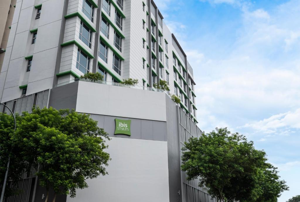 a tall white building with trees in front of it at ibis Styles Singapore Albert in Singapore