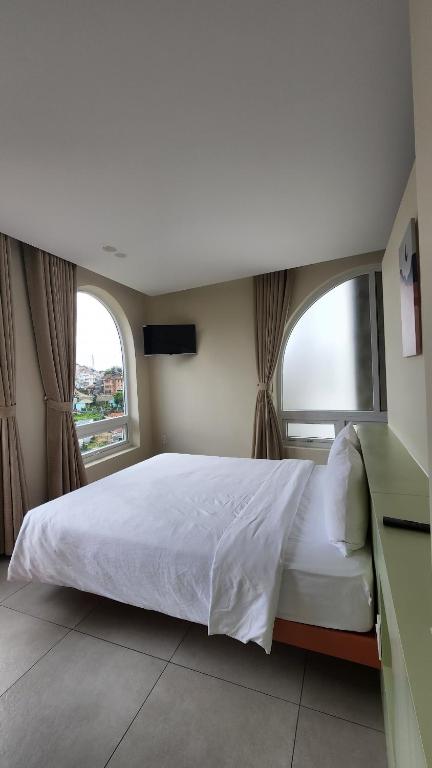 a bedroom with a large bed with a window at Raon THT Hotel in Da Lat