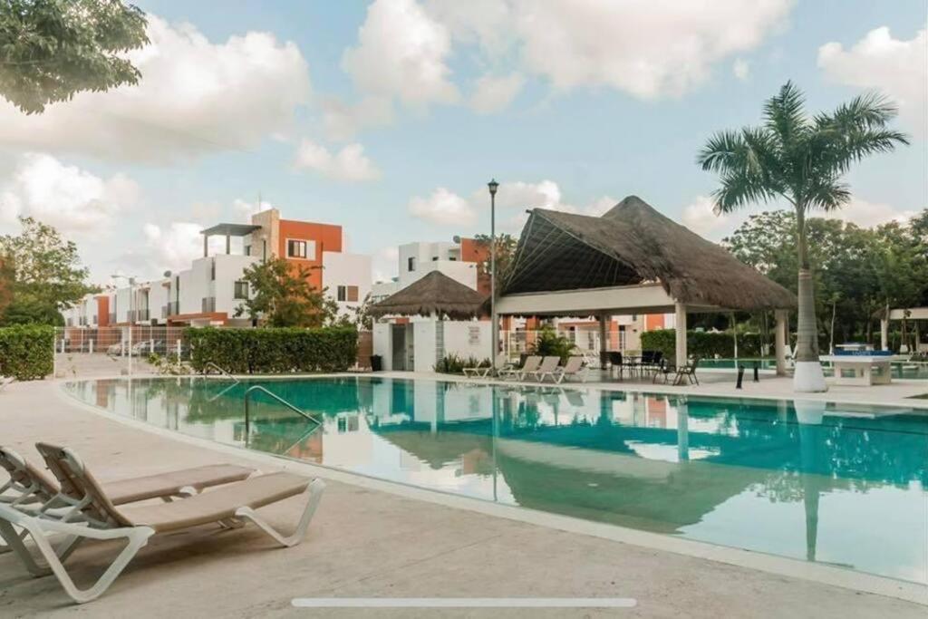 a pool at a resort with chairs and a building at Hermoso apartamento piscina, céntrico, área libre. in Cancún