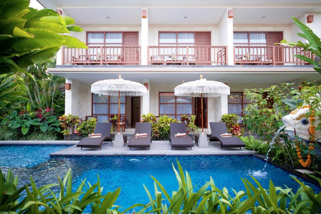 a resort with a pool and chairs and a building at Kayu Sugih Palace in Sanur
