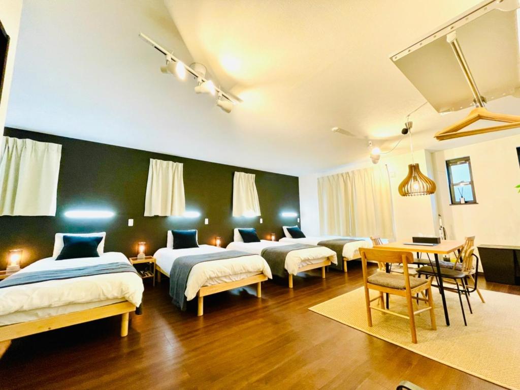 a room with four beds and a table and chairs at ホテルクラッシースカイツリー浅草曳舟 in Tokyo