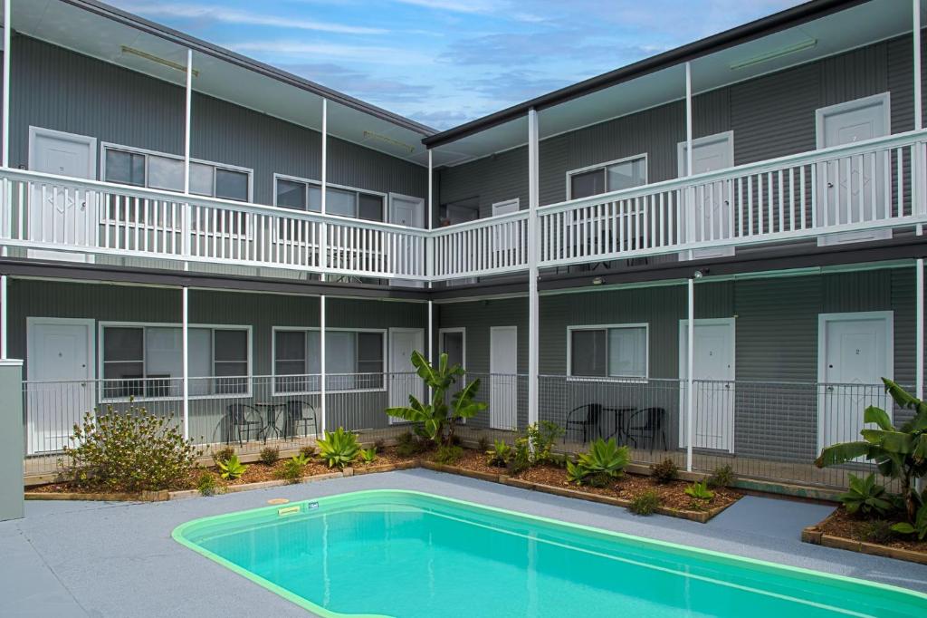 a building with a swimming pool in front of a building at Pacific Motel 09 in Forster