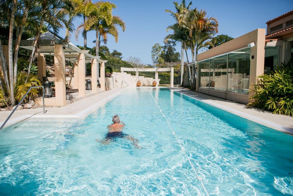 un hombre en el agua en una piscina en Noosa Springs Golf & Spa Resort en Noosa Heads