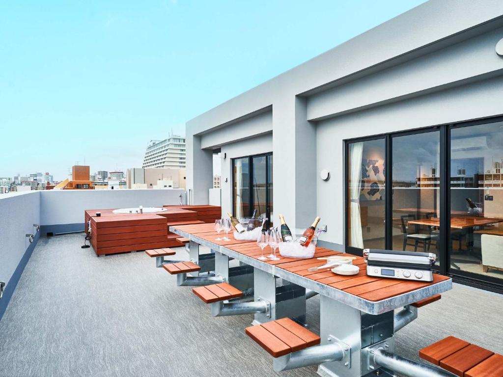 a rooftop patio with a long table and benches at Rakuten STAY Naha-Miebashi Suite Room in Naha