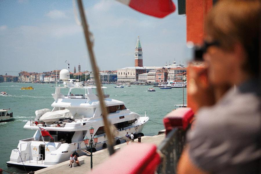 a woman is looking at boats in a harbor at La Rosa dei Venti in Venice