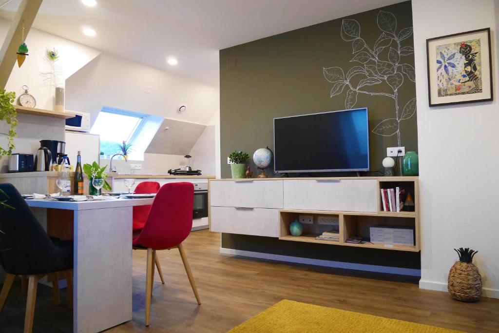 a kitchen and living room with a table and a television at Le Jardin des Roses in Saverne