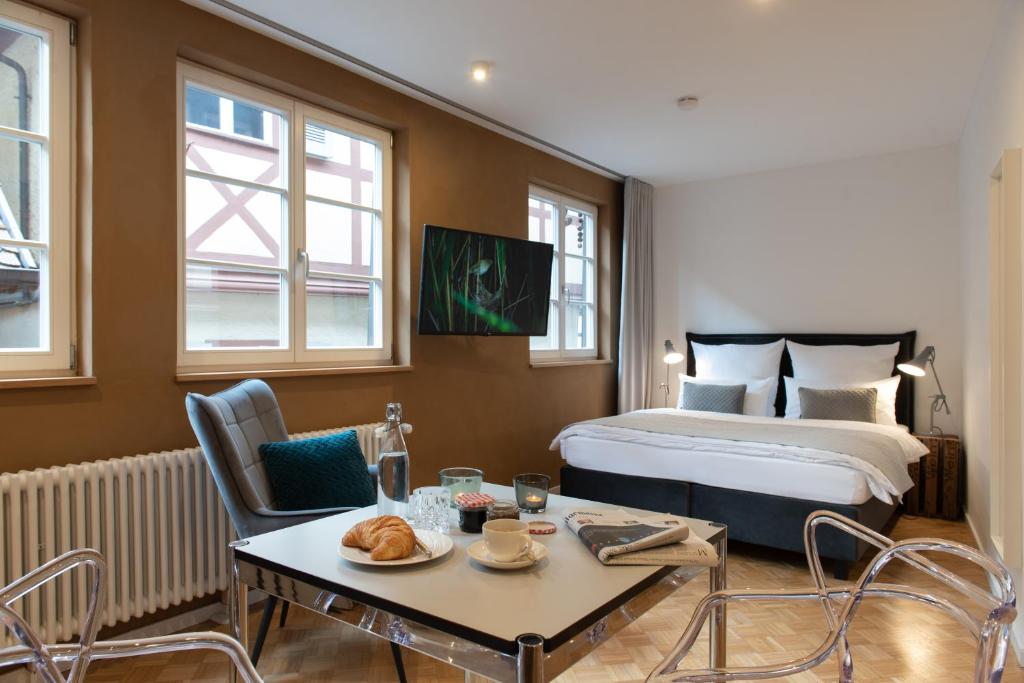 ein Hotelzimmer mit einem Bett, einem Tisch und Stühlen in der Unterkunft der Gänsbühl auf der Stadtmauer in Gengenbach