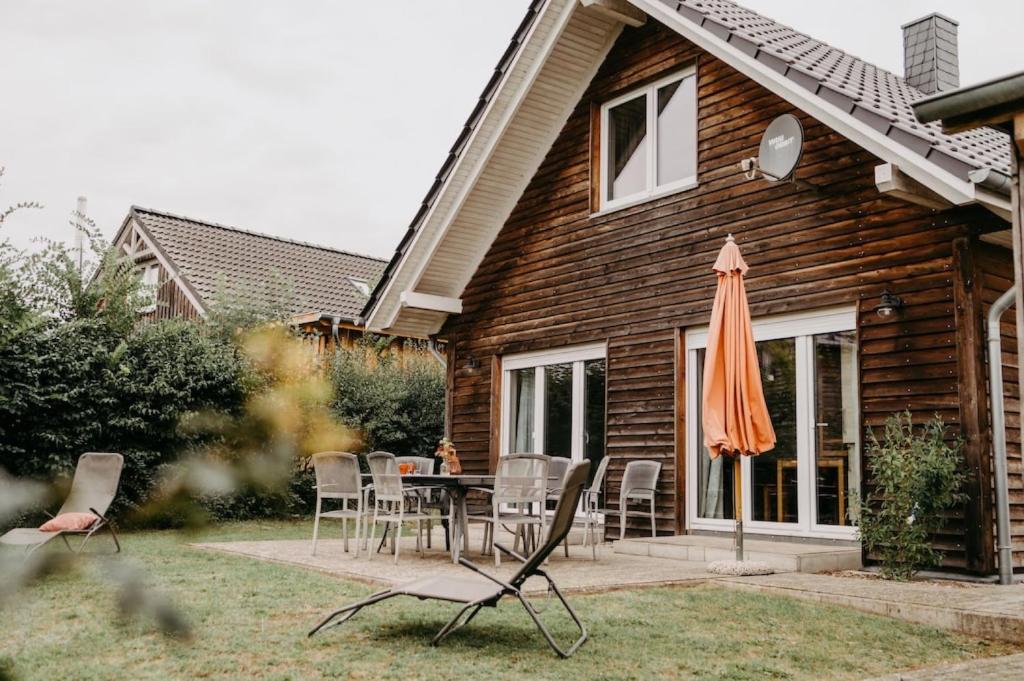 Casa de madera con mesa, sillas y sombrilla en Haus Mimi Zarrentin am Schaalsee, en Zarrentin