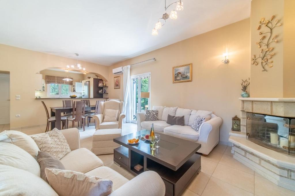 Una sala de estar con muebles blancos y chimenea. en Country House with Private Balcony, en Gouvia