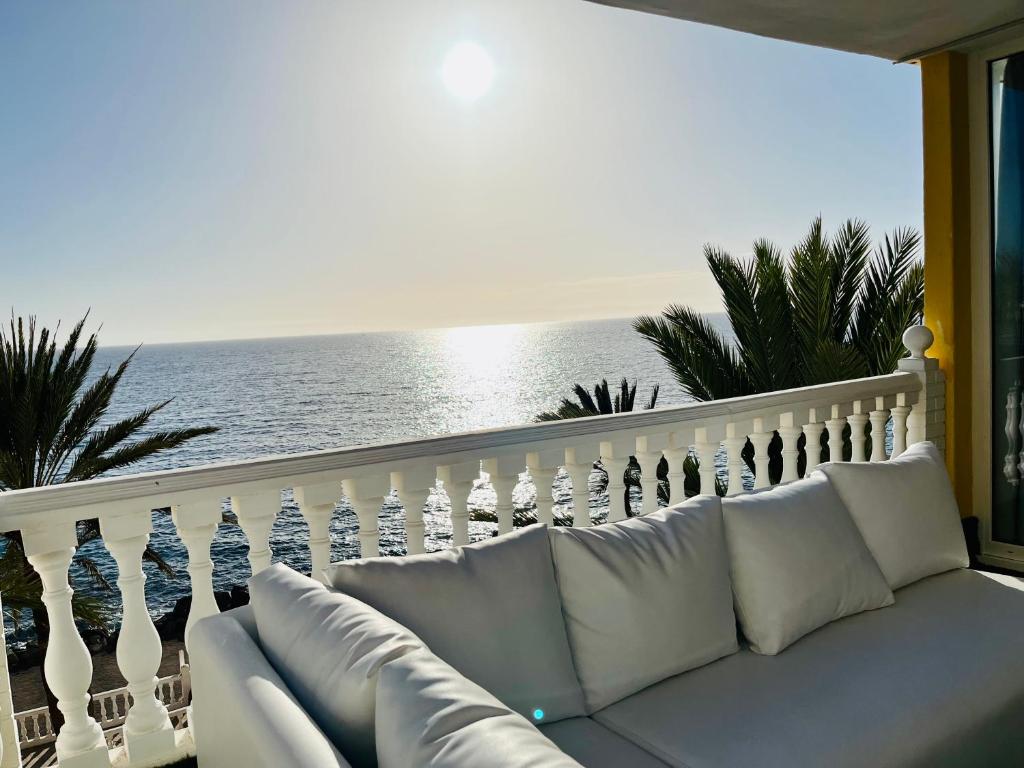 a white couch sitting on a balcony with the ocean at Luxury Sunset Ocean View in Arguineguín