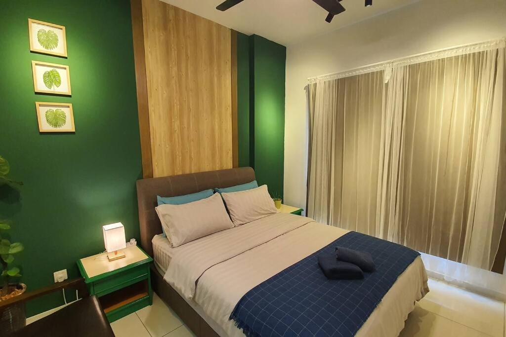 a bedroom with a bed with a green wall at Aldridge Residence Cosy Apt @EMIRA Residence in Shah Alam