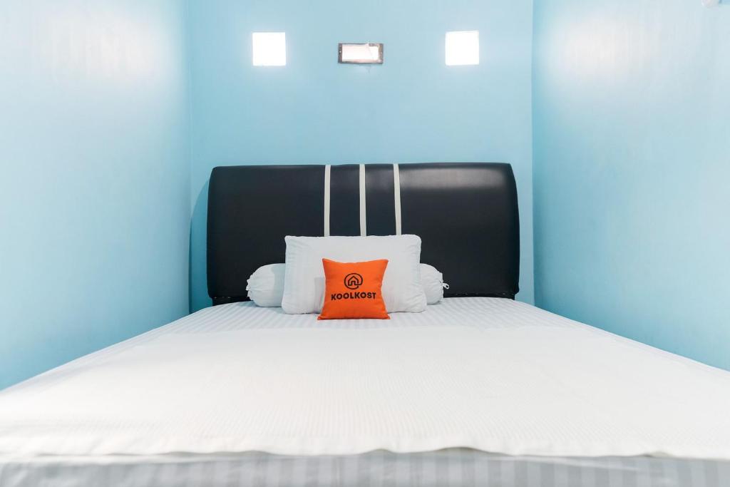 a bed with a orange pillow on top of it at KoolKost Syariah at Jelutung Jambi in Jambi