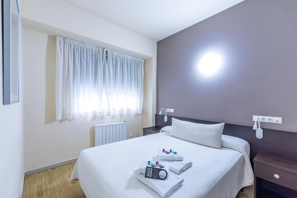 1 dormitorio con cama blanca y ventana en Residencia Universitaria Erasmo, en Madrid