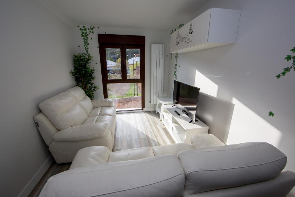 Sala de estar con 2 sofás blancos y TV en Wind Rose 10 - Moderno duplex a estrenar, en San Lorenzo de El Escorial