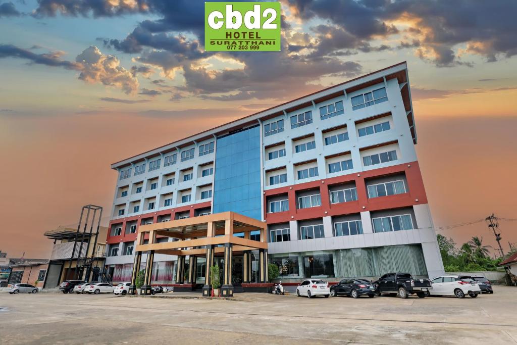 a hotel with cars parked in a parking lot at CBD 2 Hotel in Surat Thani