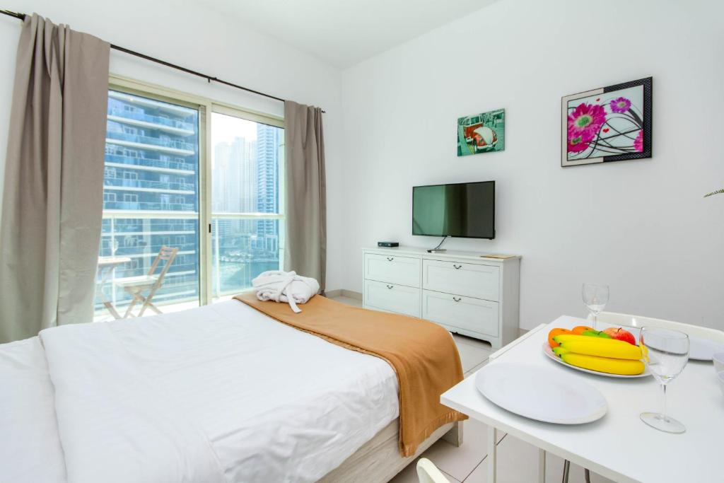 ドバイにあるBespoke Holiday Homes - Studio Apartment with Marina Viewのベッドルーム1室(ベッド1台、テーブル、フルーツプレート付)