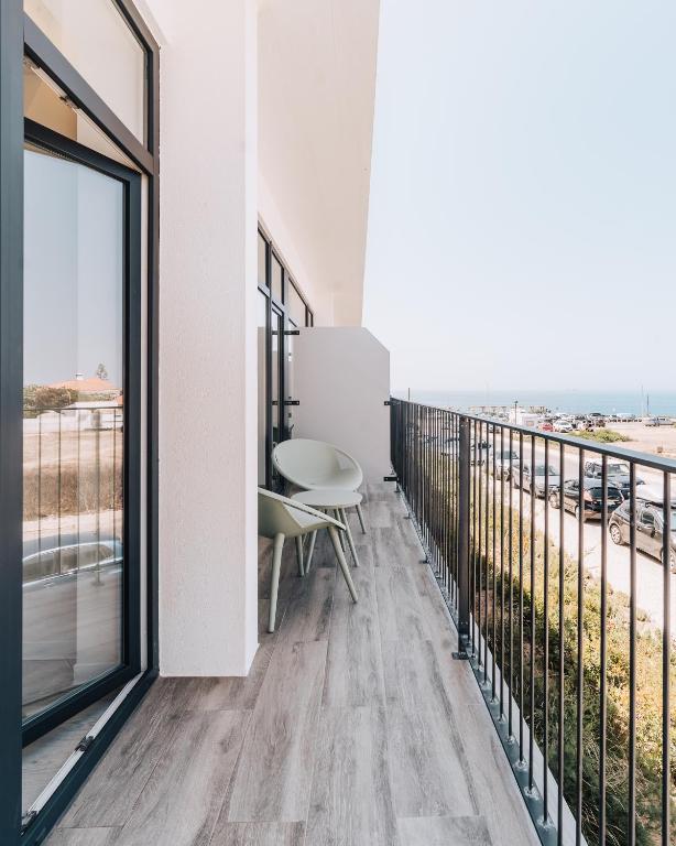 a room with a balcony with a table and chairs at Porto Covo Praia Hotel & SPA in Porto Covo
