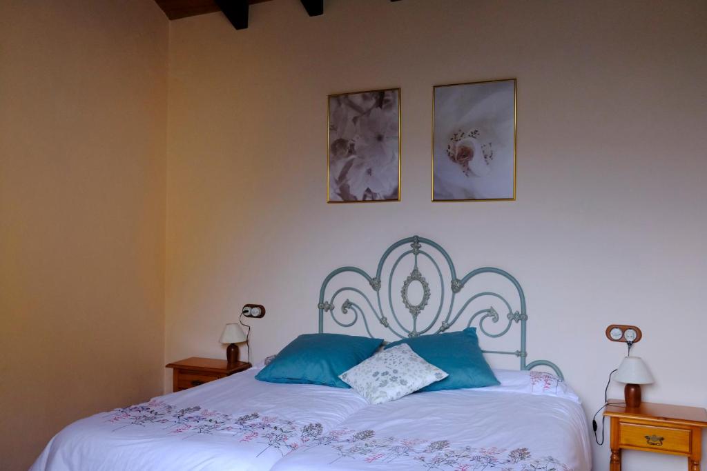 Casa Rural El Ñeru في يانس: غرفة نوم بسرير ابيض مع مخدات زرقاء