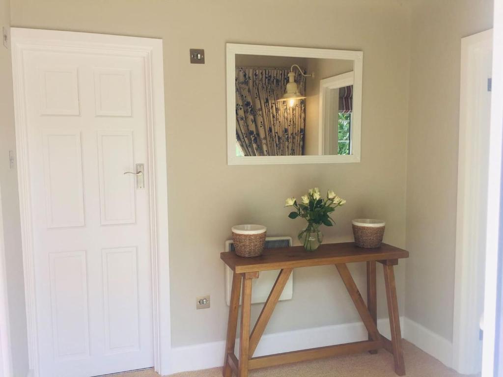 um quarto com uma mesa, um espelho e uma porta em Chadham Pines Cottage em Parkstone