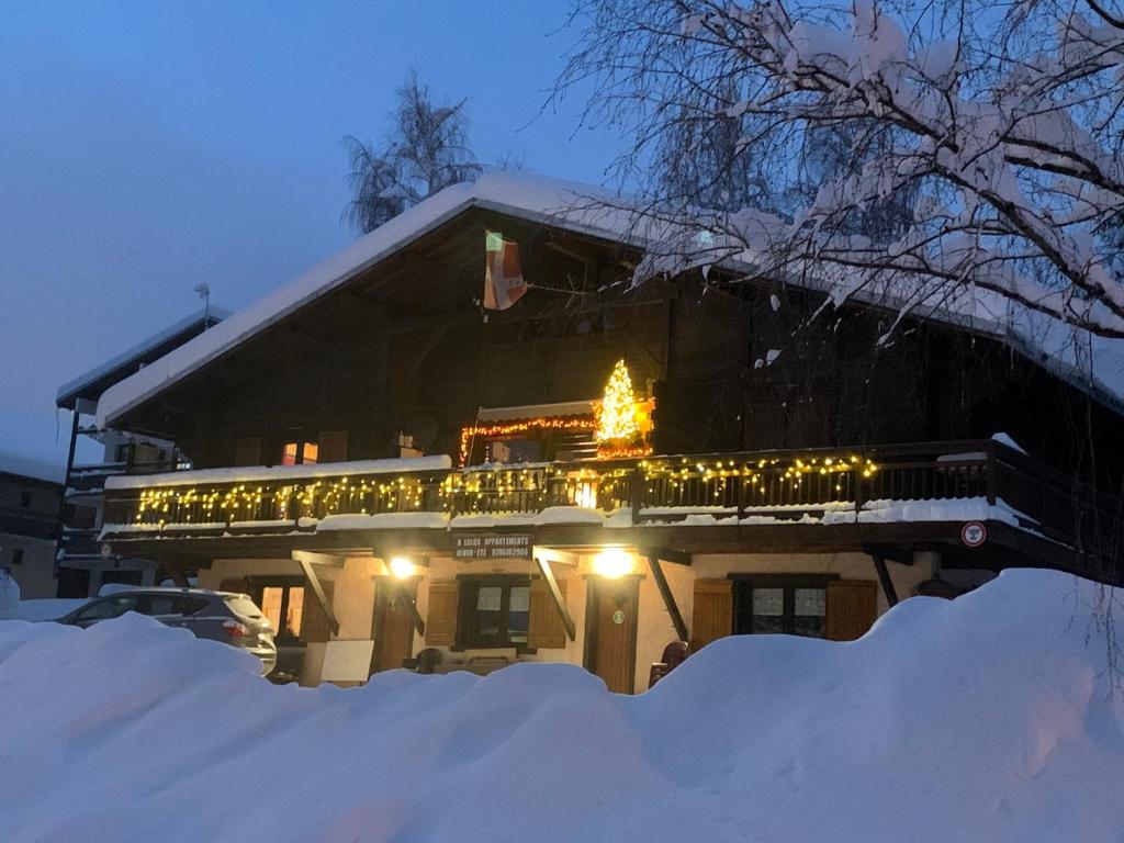 Una casa cubierta de nieve con un árbol de Navidad. en APPARTEMENT VUE SUR LES PISTES Aux SAISIES 4 en Les Saisies