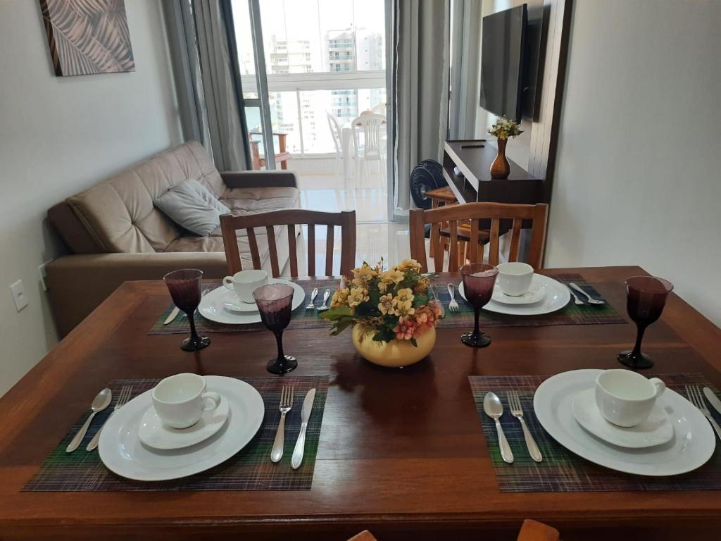 - une table à manger avec des assiettes blanches et de l'argenterie dans l'établissement Praia do Morro - Guarapari - Ap 1004 Razões, à Guarapari