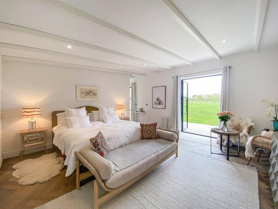 a bedroom with a bed and a couch and a window at Little Owl A beautiful bolt-hole for couples in Aldeburgh
