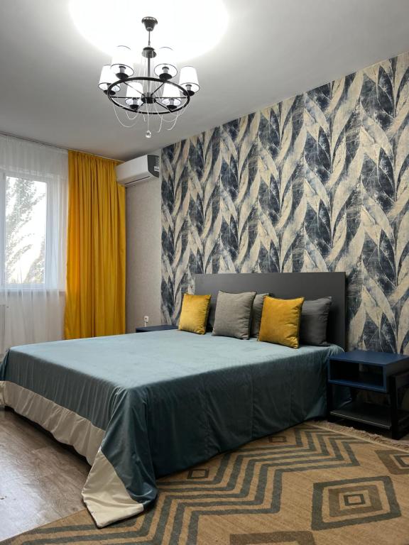 1 dormitorio con 1 cama grande con almohadas amarillas en Милая и уютная однокомнатная квартира в г.Тараз, en Taraz