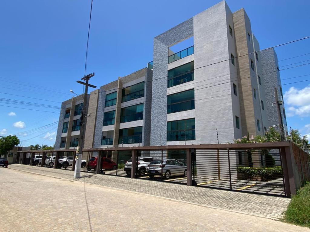 um grande edifício com carros estacionados em frente em Apartamento c/ piscina , Praia do Francês. em Marechal Deodoro