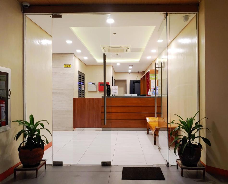 um átrio de escritório com uma porta de vidro e vasos de plantas em Kaizen Suites em Manila