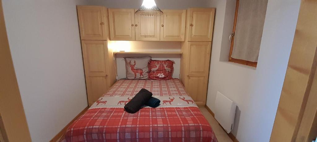 Dormitorio pequeño con cama con manta roja en Le repos du choucas, en Thollon-les-Mémises