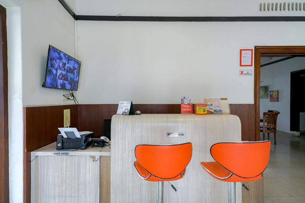 un ufficio con due sedie arancioni e una scrivania di RedDoorz @ Avros Guest House Medan a Medan