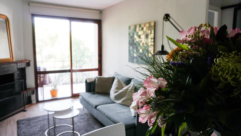 sala de estar con sofá y mesa con flores en Stylish Lakeside Apartment 1 hour from Madrid Pantano de San Juan, en San Martín de Valdeiglesias