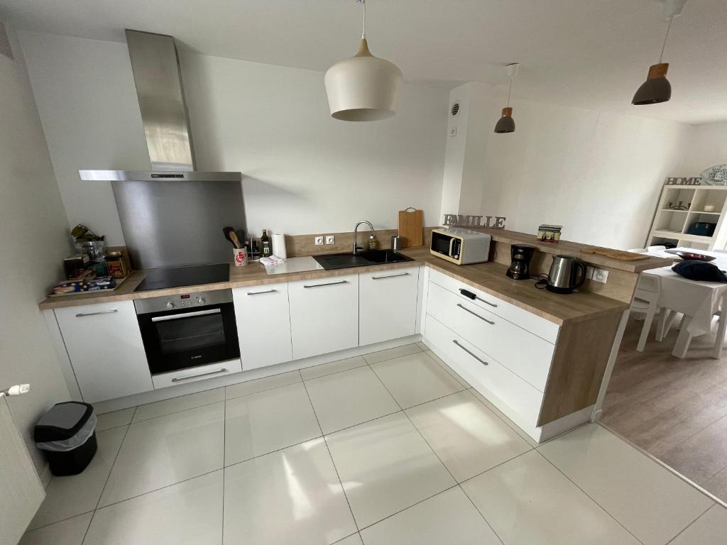 uma cozinha com armários brancos e um forno com placa de fogão em La Palmerais Dinard - 5 min de la plage em Dinard