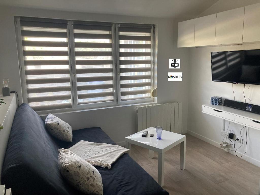 uma sala de estar com um sofá e uma mesa em Studio tout équipé au calme em Cappelle-la-Grande