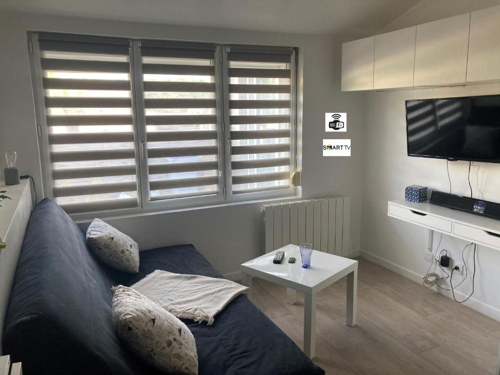 salon z kanapą i stołem w obiekcie Studio tout équipé au calme w mieście Cappelle-la-Grande