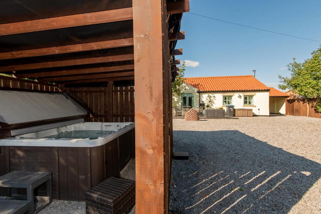 a hot tub in a wooden building with a house at East Farm Cottage in Durham