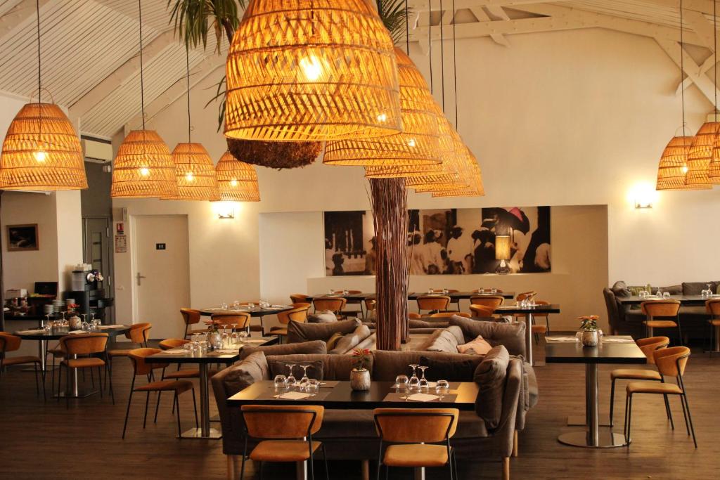 a restaurant with couches and tables and chandeliers at Hôtel Exsel Créolia in Saint-Denis