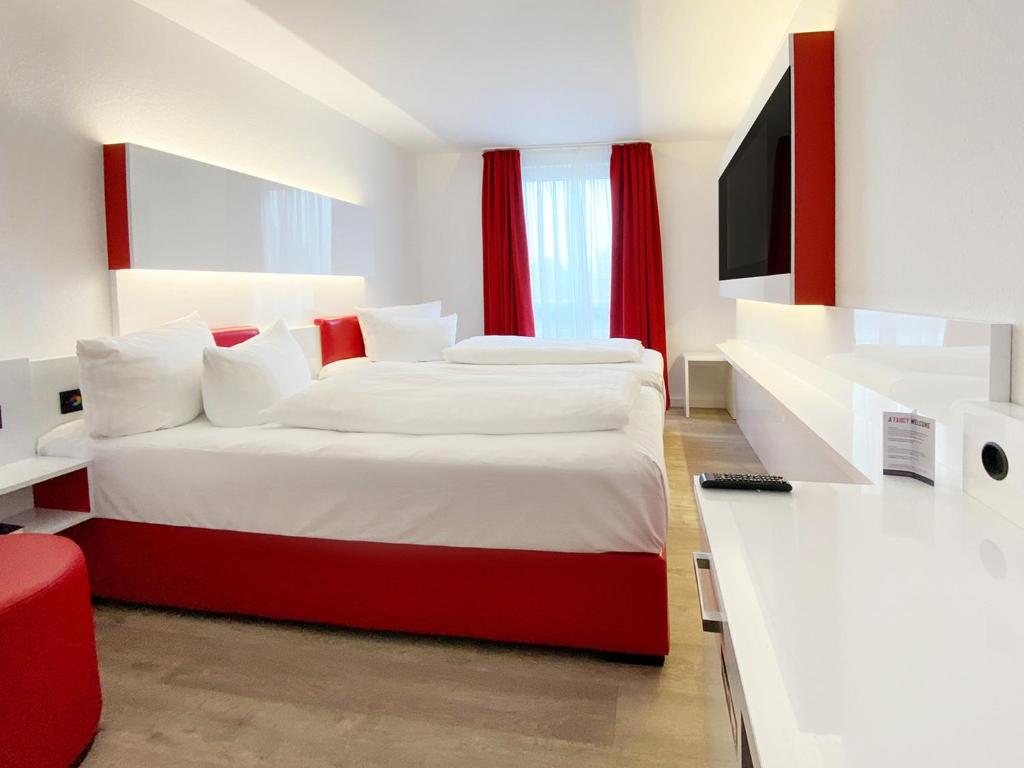 1 dormitorio con 1 cama grande y cortinas rojas en DORMERO Hotel Hoyerswerda en Hoyerswerda