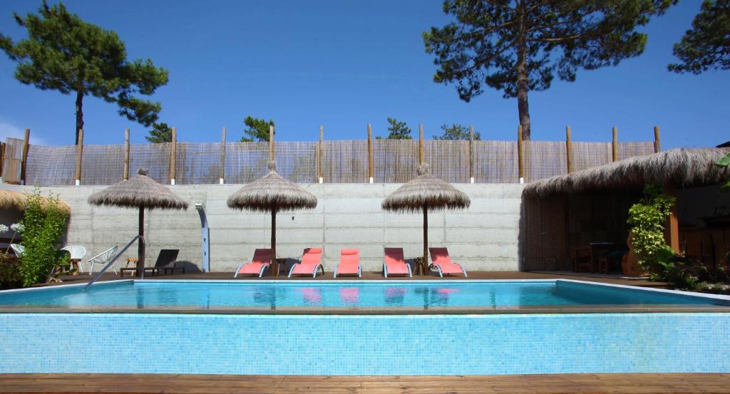 una piscina con sillas y sombrillas en The White Villa by The Getaway Collection, en Carvalhal