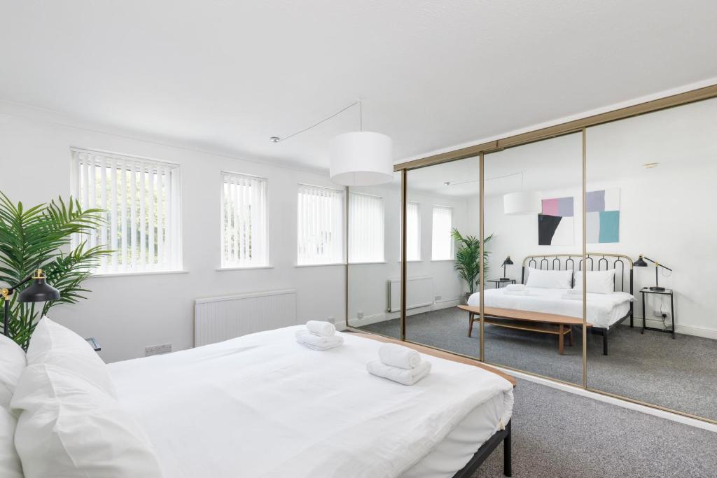 ブライトン＆ホーブにあるBeachside Retreat 2-Bedroom Gem with FREE Private Parking & Outdoor Spaceの白いベッドルーム(ベッド1台、鏡付)