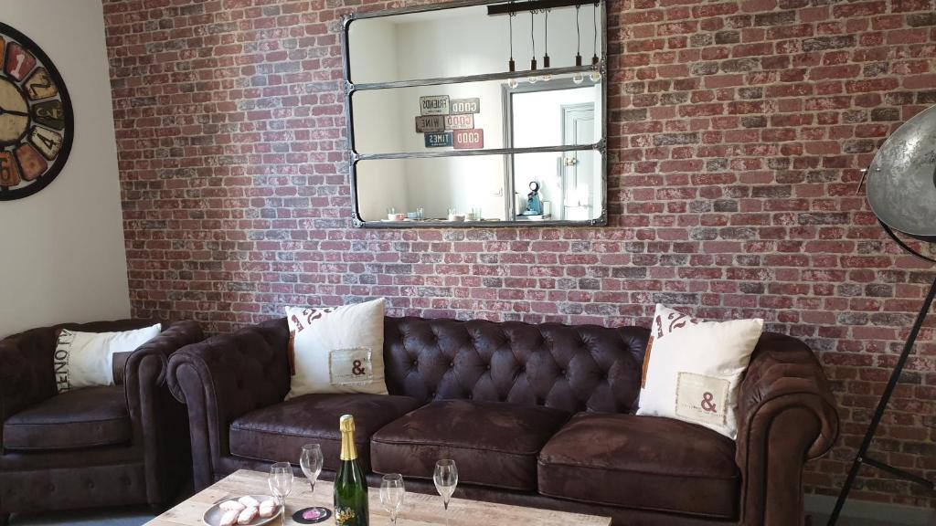 - un salon avec un canapé en cuir brun et un mur en briques dans l'établissement Le Loft Vintage Epernay avec Netflix, Vélos, Parking gratuit, à Épernay