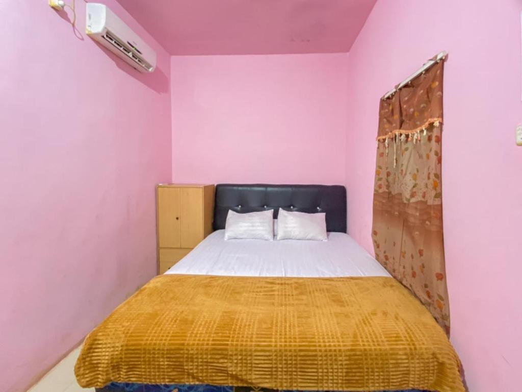 een slaapkamer met een bed in een roze kamer bij Homestay Punokawan Puncak Indah Kota Malili Mitra RedDoorz in Malili