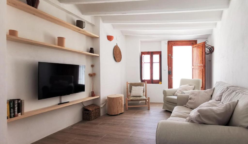 a living room with a couch and a tv on a wall at Casa El Olmo de Navajas in Navajas