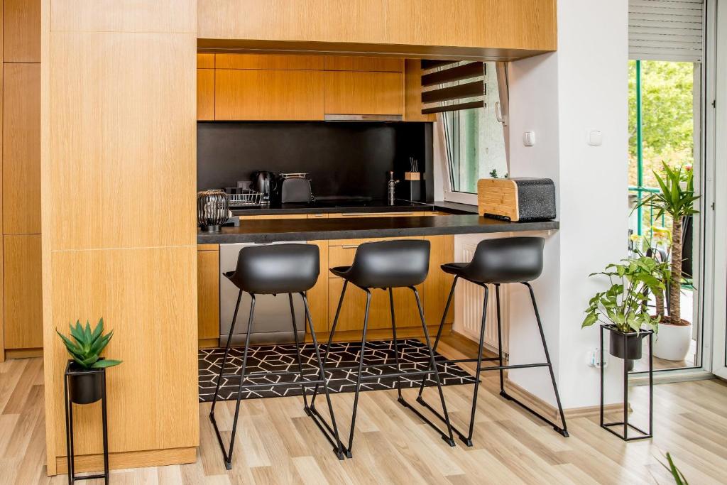 a kitchen with black stools and a counter top at Rose Gold Apartment in Zalaegerszeg