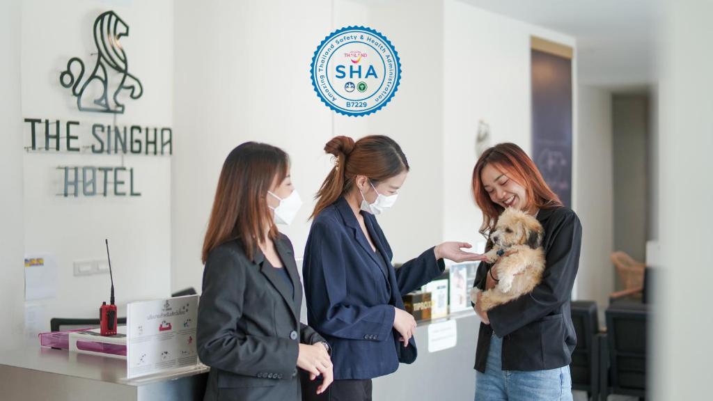 Tre donne tengono un cane in un negozio di The Singha Hotel Chiang Mai - SHA Certified a Chiang Mai