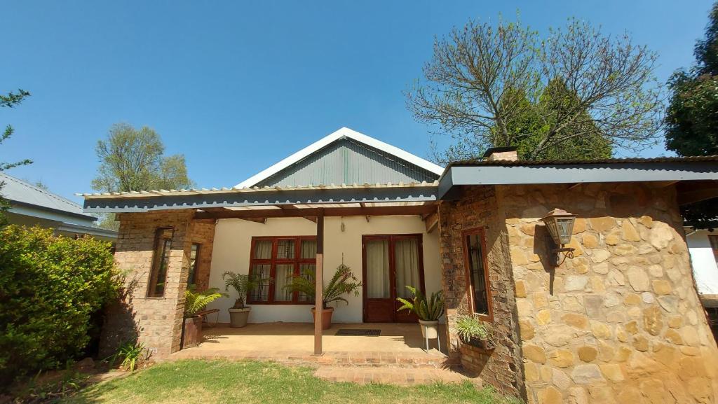 a brick house with a stone wall at Bluebell Barn in Dullstroom