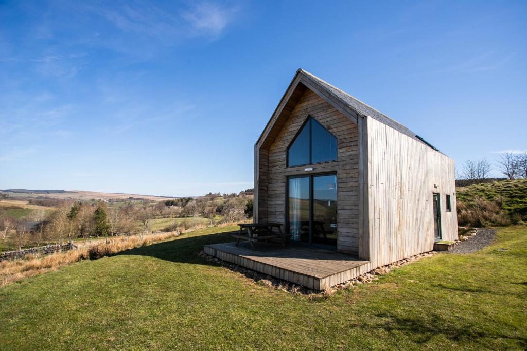 a small wooden house on a hill with a large window at Tarset Tor - Bothy 1 in Greenhaugh