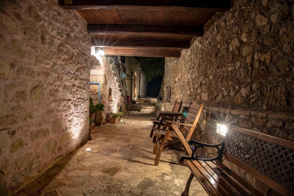 um grupo de cadeiras de madeira num corredor de pedra em STAMATOGIANNIS Traditional Apartments em Kalivianí